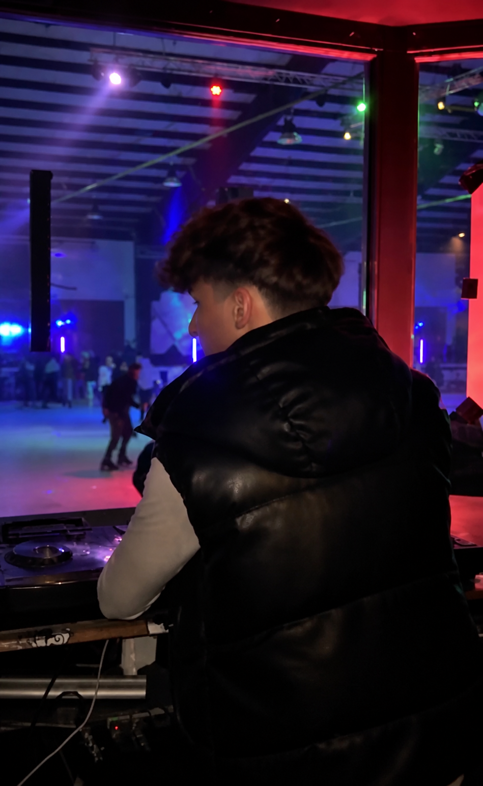 DJ Yanni am DJ-Pult mit farbiger Beleuchtung